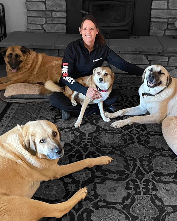 Dr. Kathy Petrucci, DVM sits on the floor with her four dogs